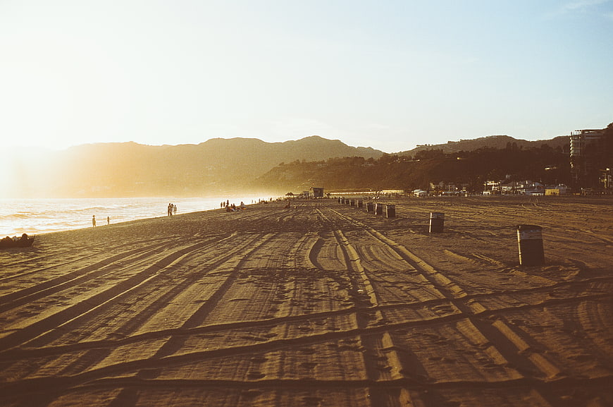 Golden Hour Beach Landscape with Sand Tracks and Distant Mountains