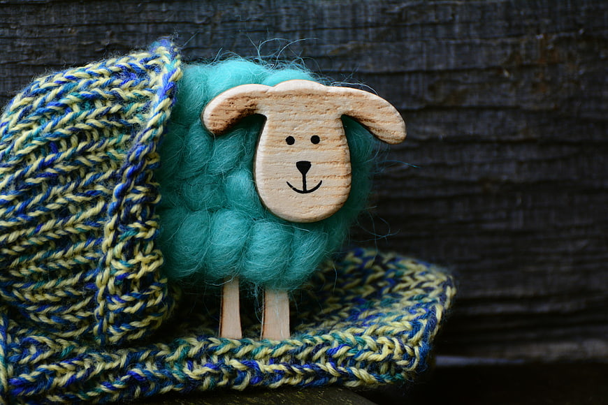 Handmade Wool Sheep Toy Wearing Knitted Hat on Dark Wood Background