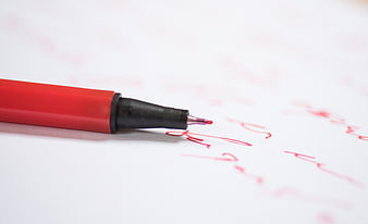Red pen writing on white paper with shallow depth of field