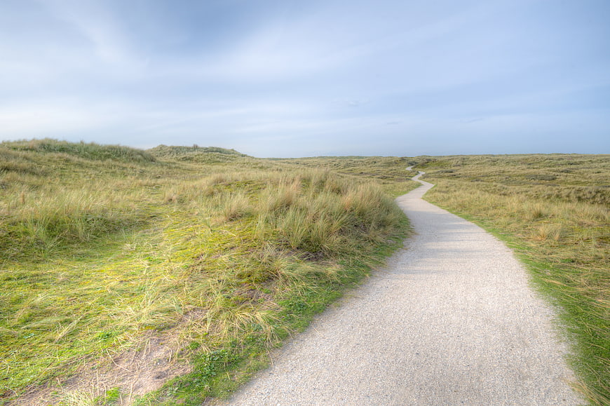 Winding gravel path through grassy dunes landscape