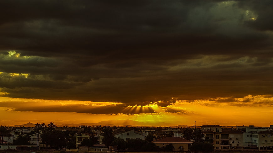 Dramatic golden sunset with sunbeams over coastal town