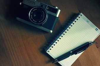 Vintage Minolta Camera, Notebook, and Pen on Wooden Desk