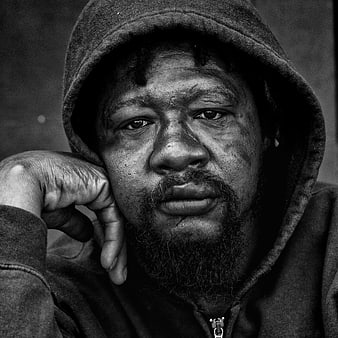 Black and white portrait of a man in a hoodie looking at camera