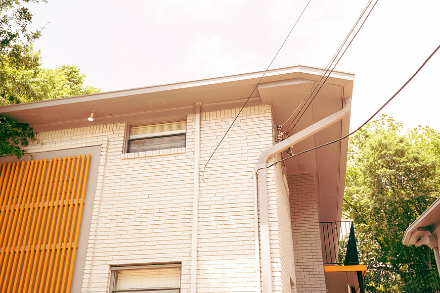 Modern White Brick House with Orange Slats and Green Trees