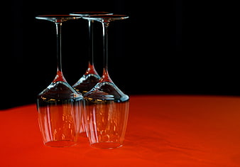 Three Upside-Down Wine Glasses on Vibrant Red Surface
