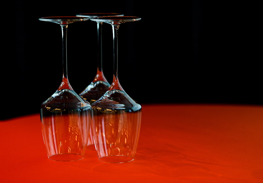 Three Upside-Down Wine Glasses on Vibrant Red Surface