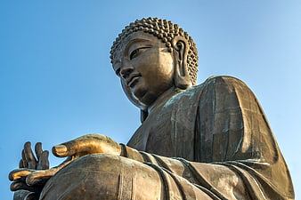Close-up of a serene bronze Buddha statue against a clear blue sky