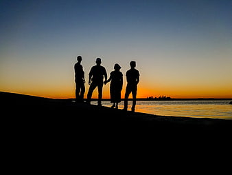 Silhouette of Four Friends Standing on Beach at Sunset