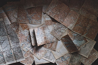 Scattered vintage antique maps on dark background