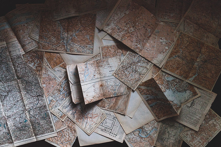 Scattered vintage antique maps on dark background