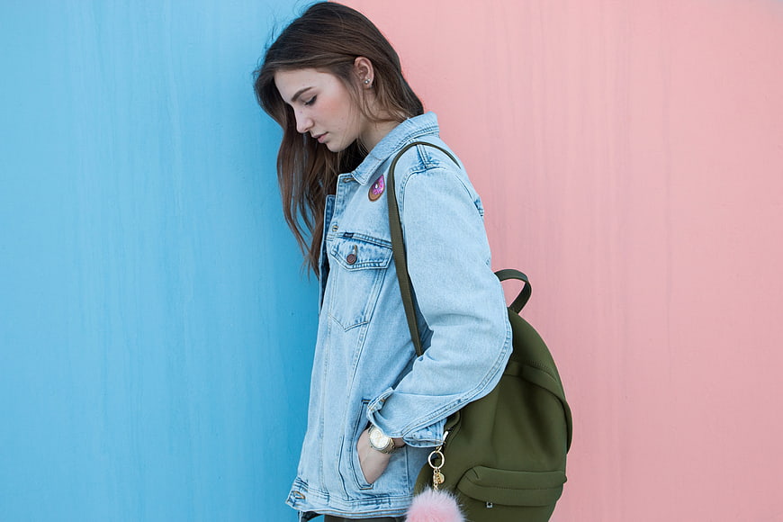 Young woman in denim jacket against blue and pink wall
