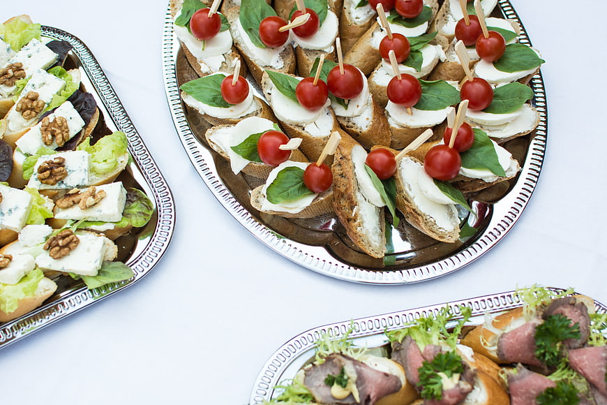 Assorted appetizers on silver platters with caprese and blue cheese