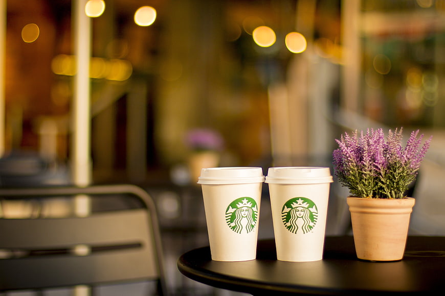 Two Starbucks coffee cups and lavender plant on cafe table