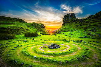 Spiral stone cairn in green Scottish highlands at sunset