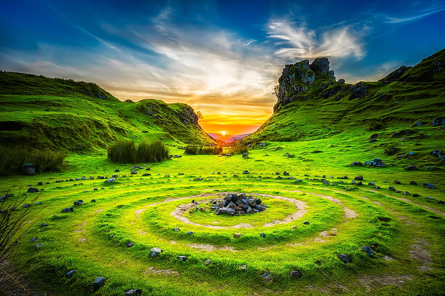 Spiral stone cairn in green Scottish highlands at sunset