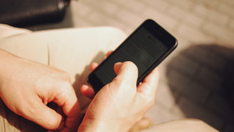 Close-up of hands holding smartphone reading text outdoors