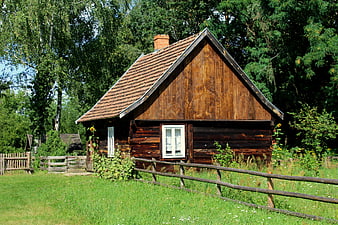Rustic wooden cottage with tiled roof in a green meadow