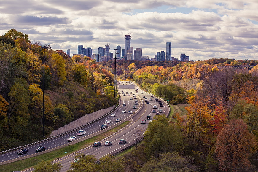 Autumn highway traffic with city skyline in distance