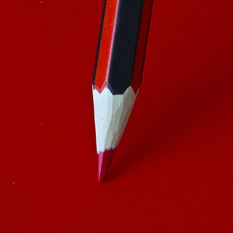 Close-up of a sharp red and black pencil on a red background