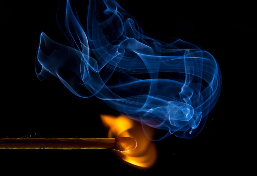 Burning Match with Blue Smoke on Black Background