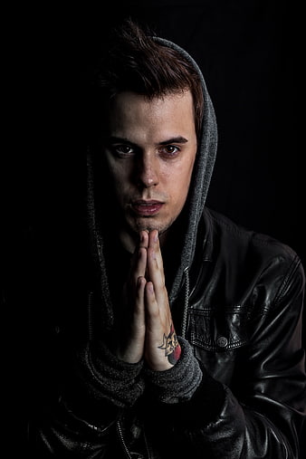 Dramatic portrait of young man in hoodie praying