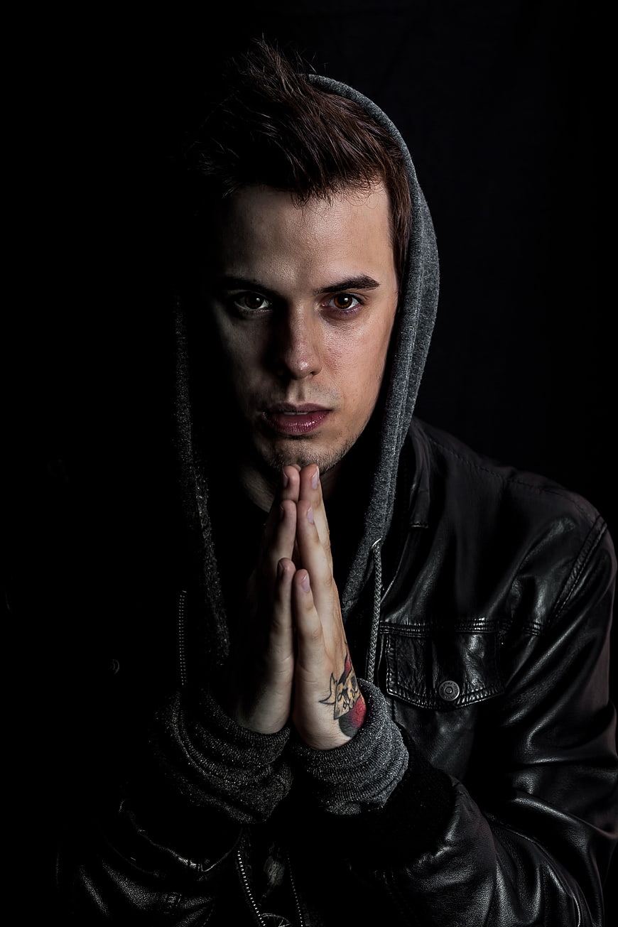 Dramatic portrait of young man in hoodie praying