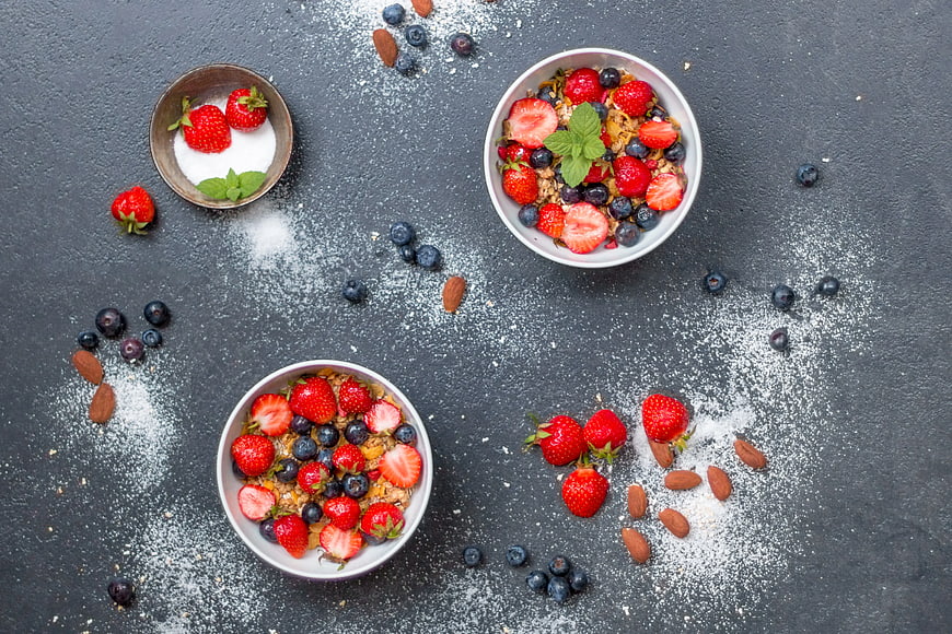 Overhead view of yogurt bowls with strawberries and blueberries