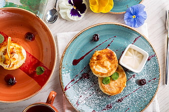 Overhead view of syrniki pancakes with berry sauce and flowers