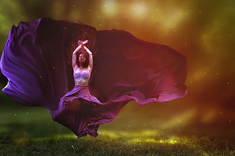 Woman dancing with flowing purple fabric in golden light