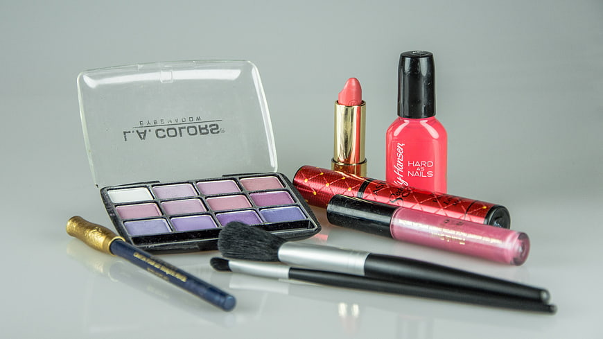 Collection of cosmetics including eyeshadow palette, lipstick, and nail polish