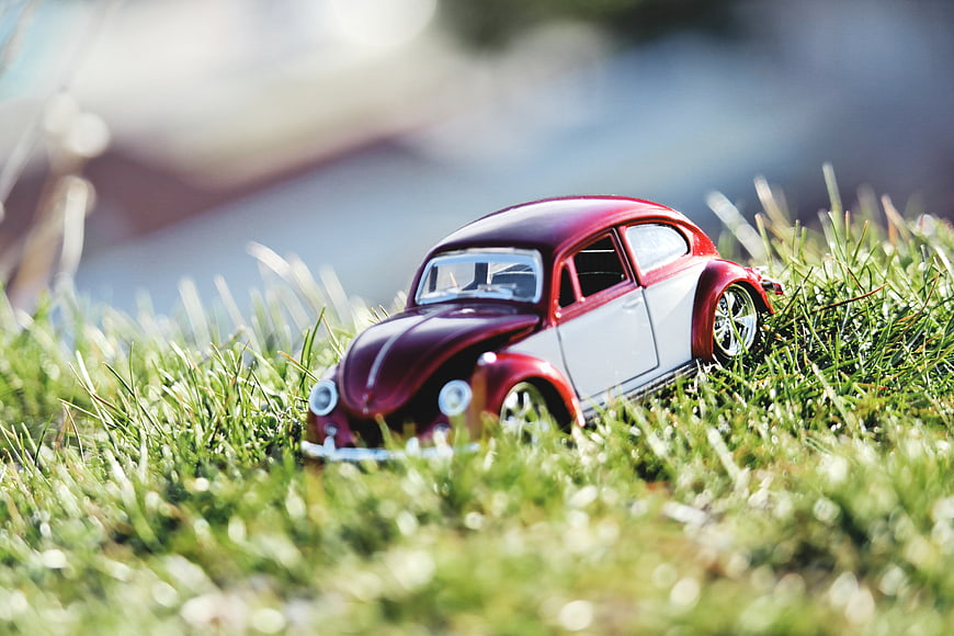 Red and white toy car on green grass
