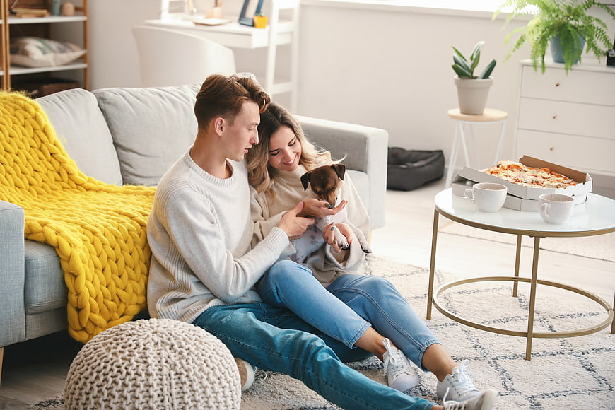Happy couple relaxing at home with dog and pizza