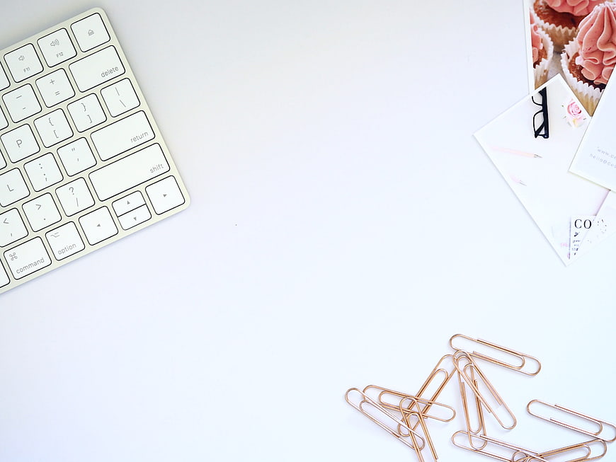 Minimalist white workspace with keyboard and rose gold paperclips