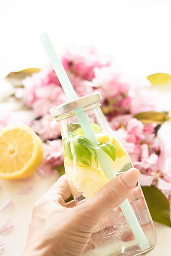 Hand holding refreshing lemon mint detox water in glass jar
