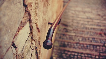 Close-up of vintage metal railing on textured stone wall