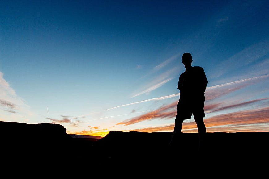 Silhouette of Man Standing on Cliff at Sunset