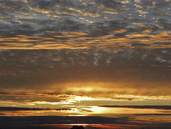 Dramatic golden sunset sky with textured clouds and silhouette