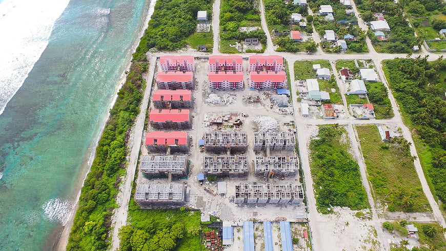 Aerial view of coastal construction site with red roofs