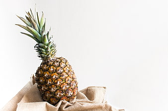 Fresh pineapple on burlap cloth with white background