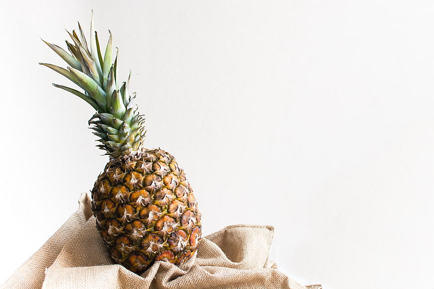 Fresh pineapple on burlap cloth with white background
