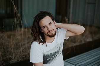 Portrait of young man with dreadlocks sitting outdoors