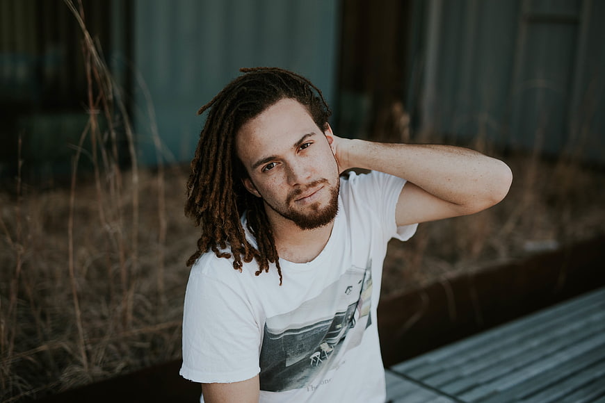 Portrait of young man with dreadlocks sitting outdoors