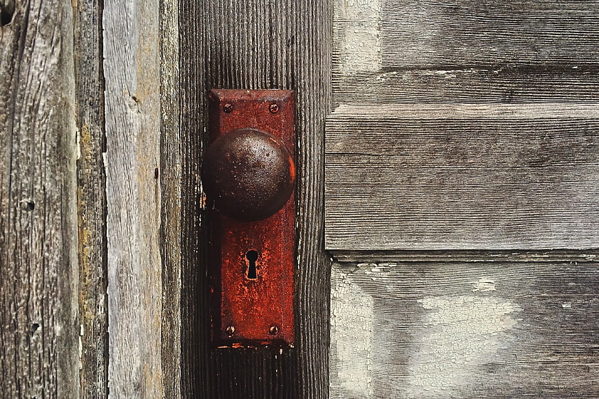 Rusty vintage door knob on weathered wooden planks
