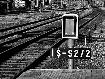 Black and white railway signal with tracks curving into distance