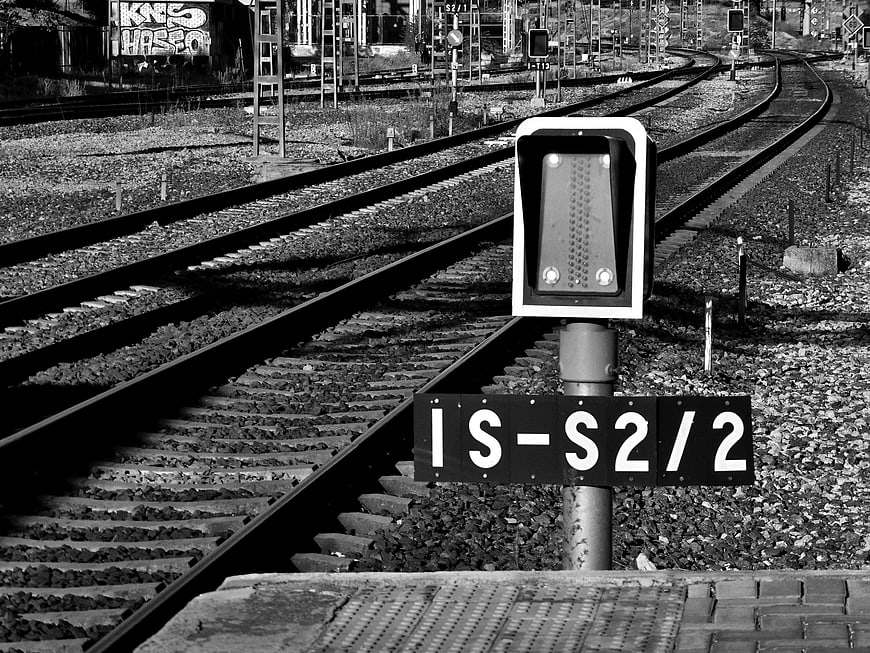 Black and white railway signal with tracks curving into distance