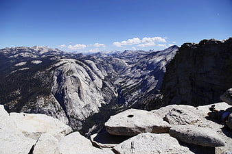 Hiker resting on granite cliff edge overlooking mountain valley