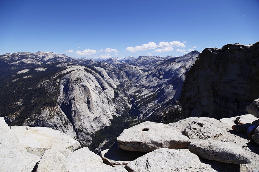 Hiker resting on granite cliff edge overlooking mountain valley