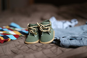 Green Baby Boots with Clothes on Bed