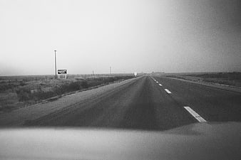 Vintage black and white highway driving view with Quaker State sign