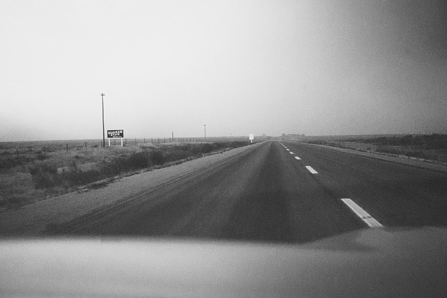 Vintage black and white highway driving view with Quaker State sign